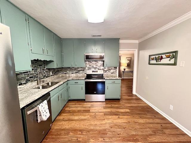 2401 Mexia Ave, Tallahassee, FL 32304 - kitchen with stainless steel appliances, a sink, exhaust hood, backsplash, and crown molding
