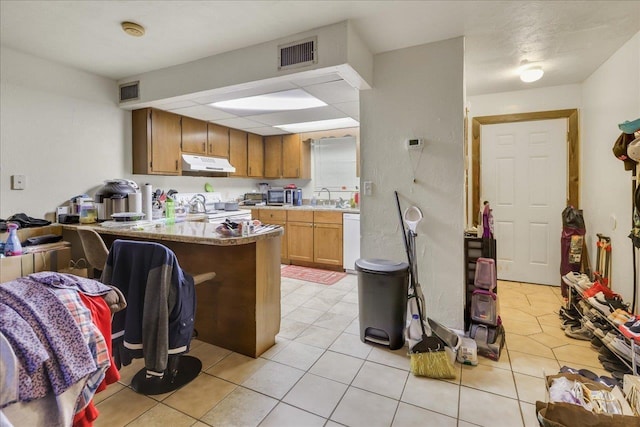 1292 Rumba Ln -, Unit Tallahassee, FL 32304 - kitchen featuring under cabinet range hood, white appliances, a peninsula, light tile patterned floors, and light countertops