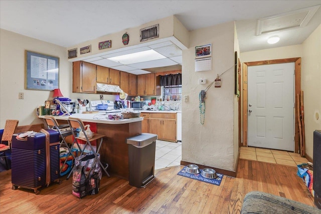 1292 Rumba Ln -, Unit Tallahassee, FL 32304 - kitchen featuring white range oven, stainless steel microwave, light wood-style flooring, under cabinet range hood, and a peninsula