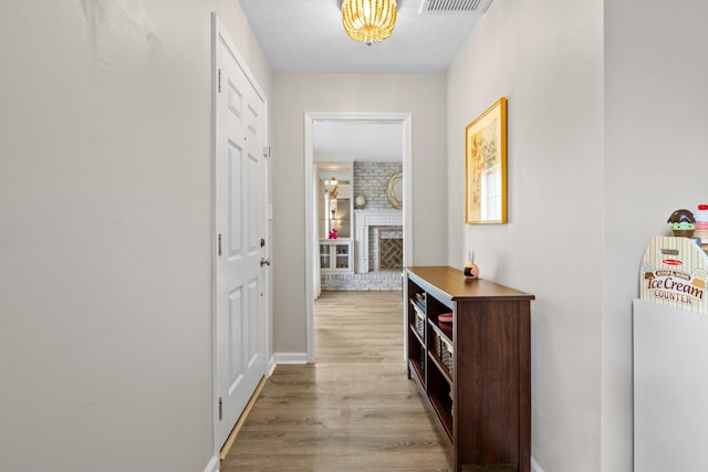 hall with wood finished floors, visible vents, and baseboards