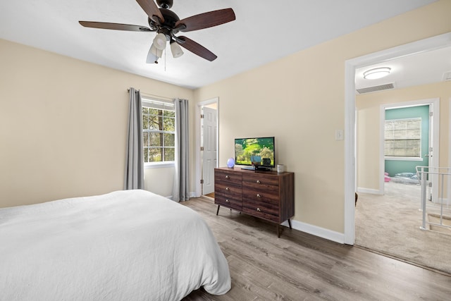 bedroom with a ceiling fan, wood finished floors, visible vents, and baseboards