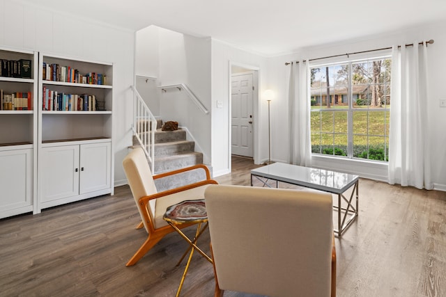 sitting room featuring stairs, ornamental molding, and wood finished floors