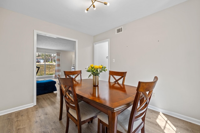 dining room featuring light wood-style floors, baseboards, and visible vents