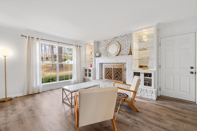 living area with crown molding, a fireplace, built in features, and wood finished floors