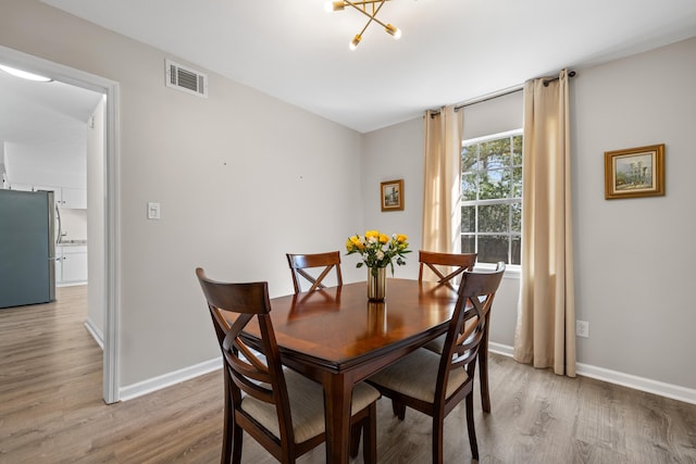 dining room featuring light wood-type flooring, baseboards, and visible vents