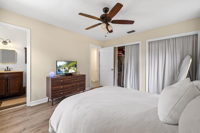 bedroom featuring baseboards, visible vents, light wood-style flooring, ceiling fan, and a sink