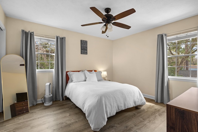 bedroom featuring ceiling fan, baseboards, and wood finished floors