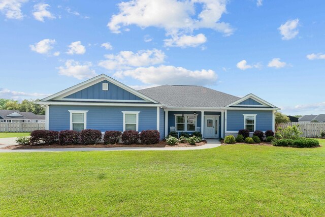 ranch-style house with board and batten siding, fence, and a front lawn