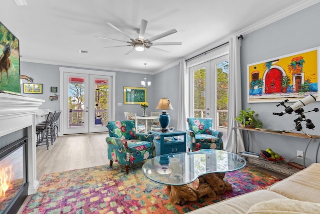 living room featuring french doors, ceiling fan, ornamental molding, and light hardwood / wood-style flooring