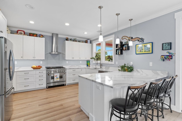 kitchen with a kitchen breakfast bar, stainless steel appliances, white cabinets, kitchen peninsula, and wall chimney exhaust hood