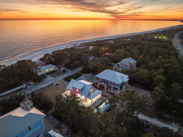 aerial view at dusk with a water view and a beach view