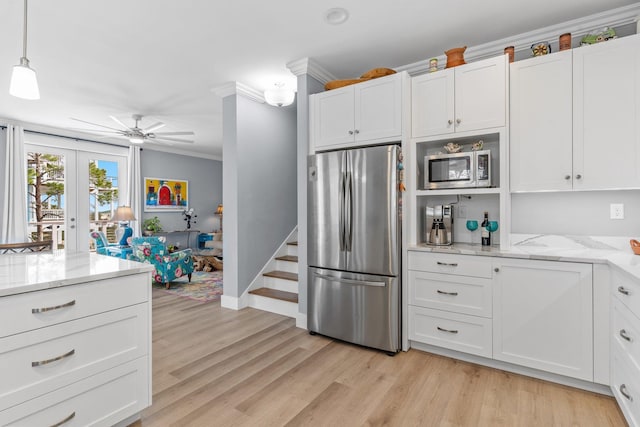 kitchen featuring pendant lighting, white cabinets, stainless steel appliances, crown molding, and light stone countertops