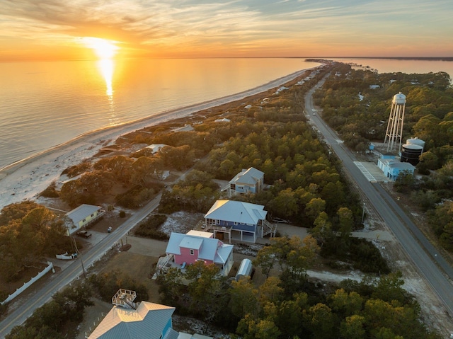 aerial view at dusk featuring a water view and a view of the beach