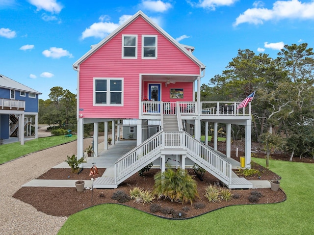 back of property with ceiling fan, a porch, and a lawn