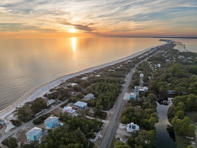 aerial view at dusk featuring a view of the beach and a water view