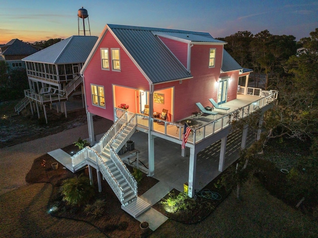 back house at dusk featuring a deck and a patio area