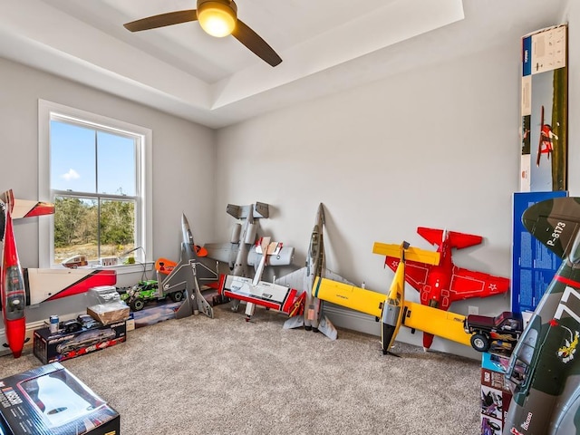 playroom with a tray ceiling, ceiling fan, and carpet