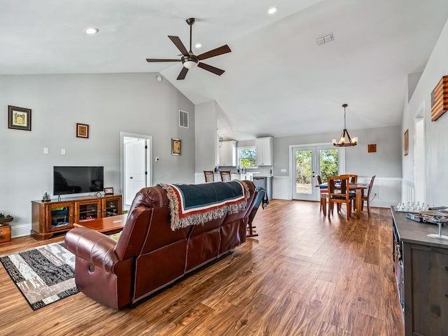 living room featuring hardwood / wood-style flooring, ceiling fan with notable chandelier, high vaulted ceiling, and french doors