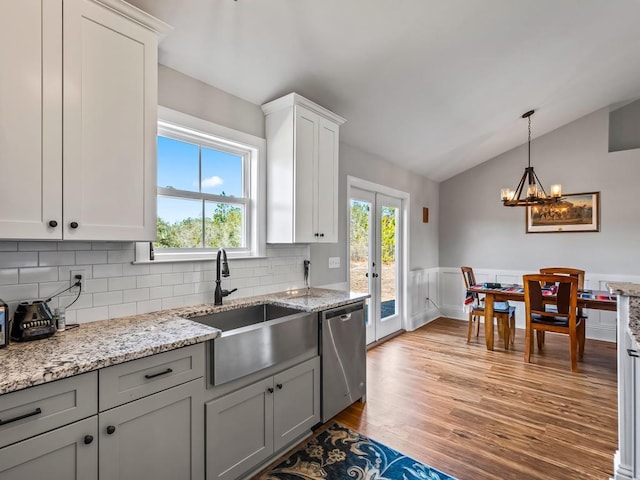 kitchen featuring lofted ceiling, sink, light wood-type flooring, stainless steel dishwasher, and white cabinets