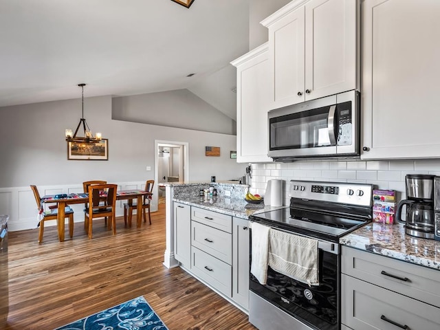 kitchen with light stone countertops, white cabinetry, appliances with stainless steel finishes, and dark hardwood / wood-style floors