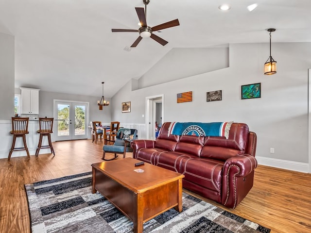 living room featuring wood-type flooring, french doors, ceiling fan, and vaulted ceiling