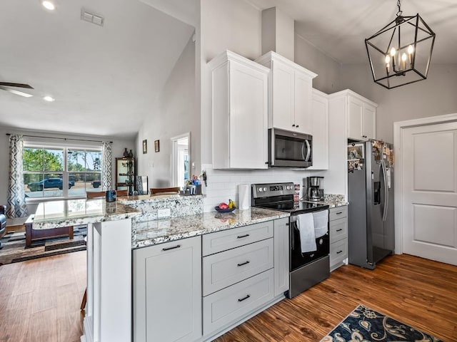 kitchen featuring white cabinetry, a kitchen bar, dark hardwood / wood-style flooring, kitchen peninsula, and stainless steel appliances