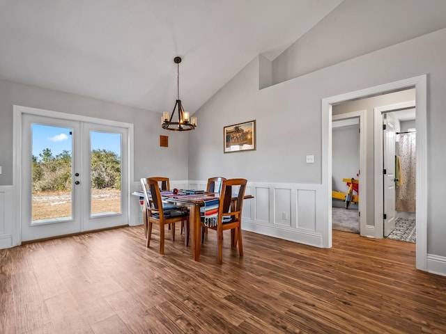 dining space featuring french doors, lofted ceiling, dark hardwood / wood-style flooring, and an inviting chandelier