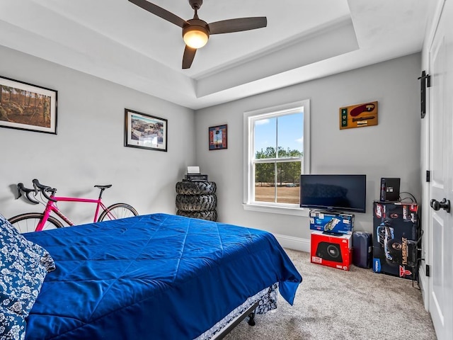 carpeted bedroom featuring a raised ceiling and ceiling fan