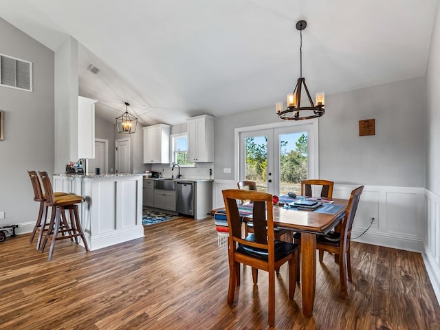 dining area with lofted ceiling, sink, a chandelier, dark wood-type flooring, and french doors