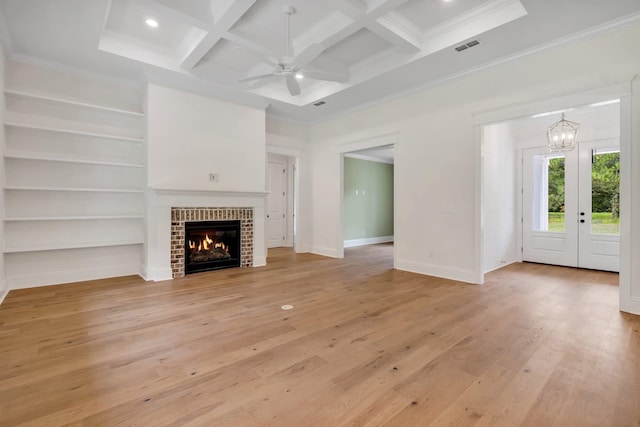 unfurnished living room featuring coffered ceiling, ornamental molding, a brick fireplace, beamed ceiling, and light wood-type flooring