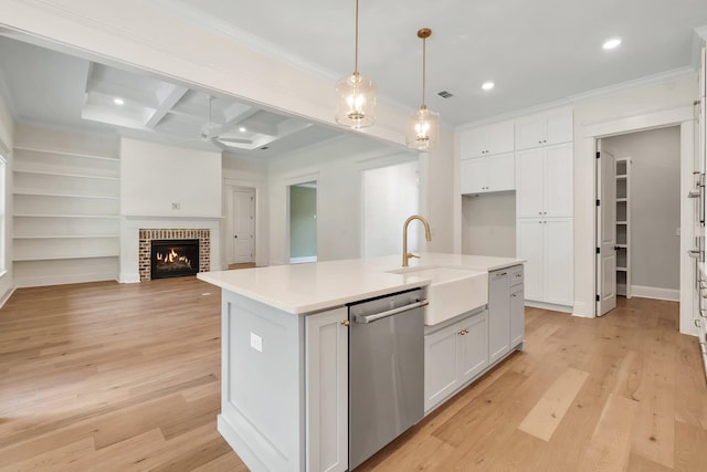 kitchen featuring sink, white cabinetry, hanging light fixtures, stainless steel dishwasher, and an island with sink