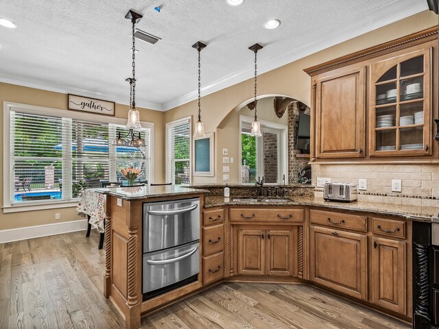 kitchen with light wood-type flooring, stone countertops, decorative light fixtures, and a textured ceiling