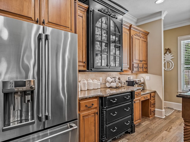 kitchen with a textured ceiling, stainless steel fridge with ice dispenser, ornamental molding, light hardwood / wood-style flooring, and dark stone countertops