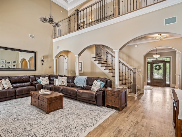 living room featuring ornamental molding, light wood-type flooring, a high ceiling, and an inviting chandelier