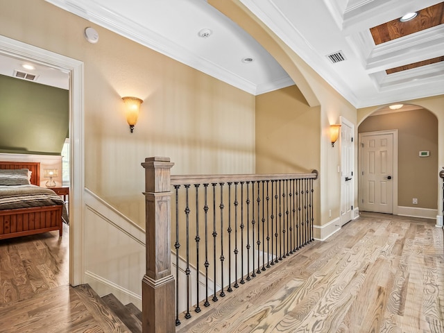 hallway featuring coffered ceiling, light hardwood / wood-style floors, ornamental molding, and beam ceiling