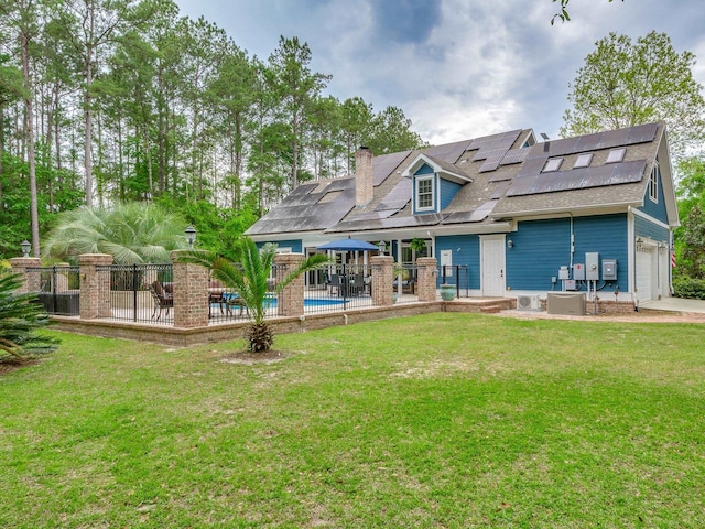 rear view of house with solar panels, a lawn, and a patio