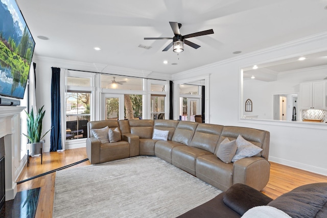 living room featuring ceiling fan, light hardwood / wood-style floors, and crown molding