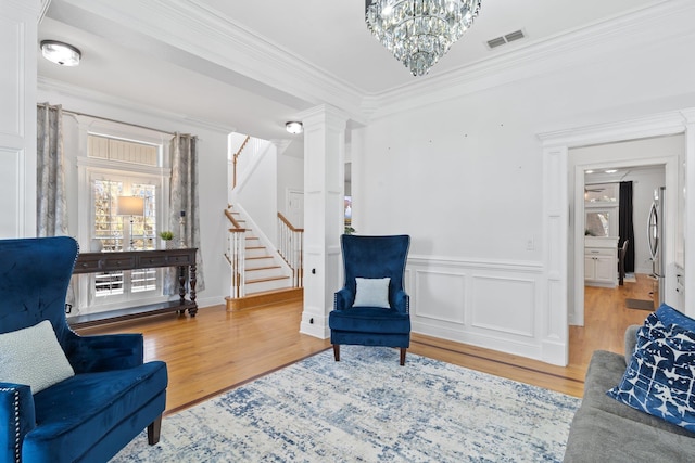 sitting room with hardwood / wood-style floors, ornate columns, and ornamental molding