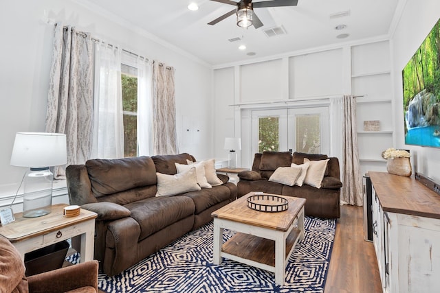 living room with french doors, built in shelves, ceiling fan, crown molding, and dark hardwood / wood-style floors