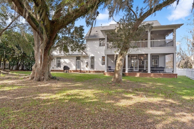 back of property with ceiling fan, a lawn, and a sunroom