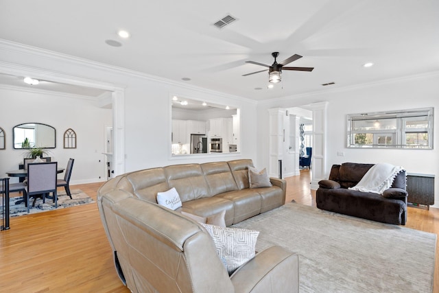 living room featuring radiator, ceiling fan, light hardwood / wood-style floors, crown molding, and ornate columns