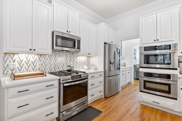 kitchen with white cabinetry, ornamental molding, tasteful backsplash, and stainless steel appliances