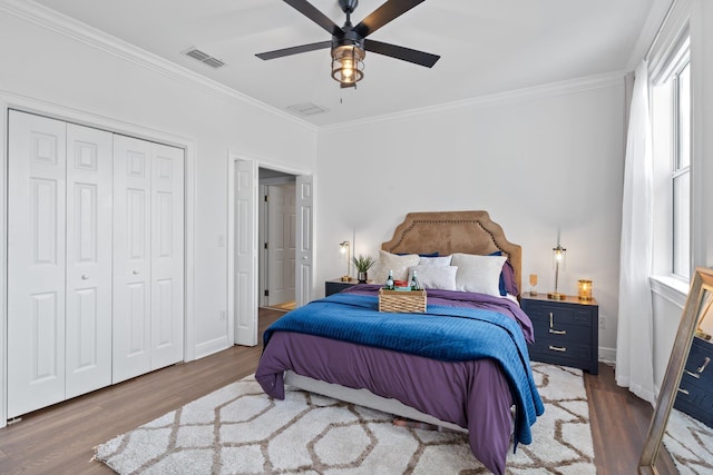 bedroom with ceiling fan, dark wood-type flooring, crown molding, and a closet