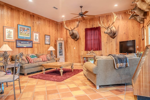 living room with wooden walls, ceiling fan, and light tile patterned flooring