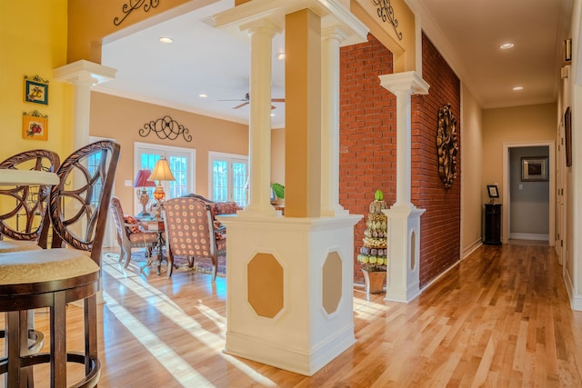 hallway featuring light wood-type flooring, ornamental molding, and brick wall