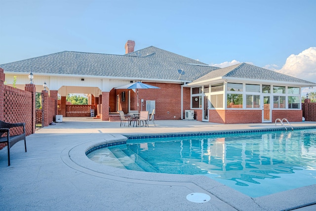 view of pool featuring central air condition unit, a sunroom, and a patio area