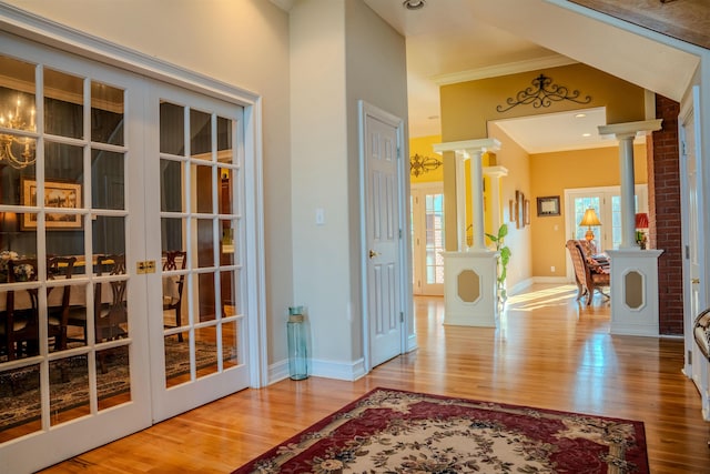 entrance foyer with decorative columns, wood-type flooring, a healthy amount of sunlight, and crown molding