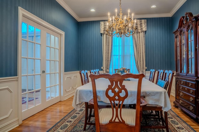 dining space with a notable chandelier, ornamental molding, and light hardwood / wood-style flooring