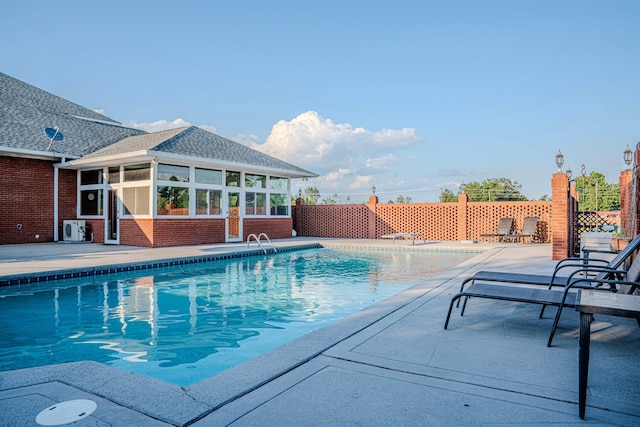 view of swimming pool featuring a patio and a sunroom