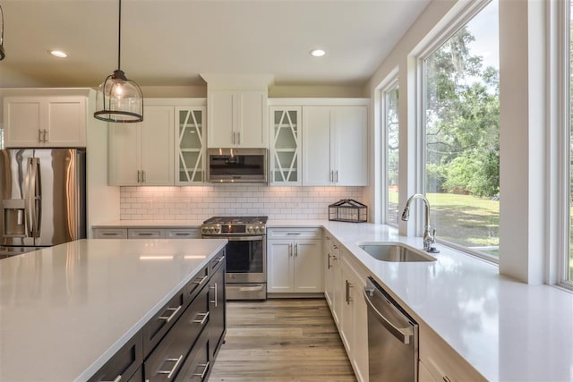 kitchen with white cabinets, stainless steel appliances, hanging light fixtures, and sink